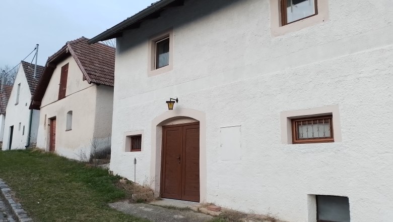Exterior view, © Wein-Bleibe Rows of white houses with brown doors and windows, along a street with grass verges.