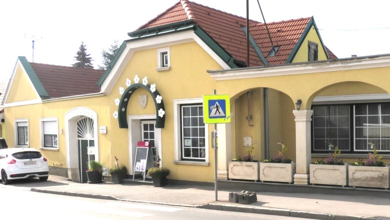 Exterior view of a yellow building with arcades and a red roof.