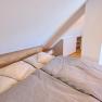 Attic bedroom with double bed and wooden floor.