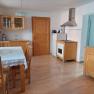 Kitchen with wooden furniture, dining table, chairs, stove, fridge and wall cupboard.