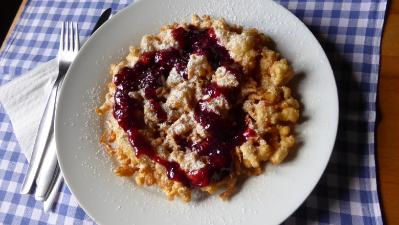 A plate of Kaiserschmarrn and red fruit jelly on a blue and white checked cloth.