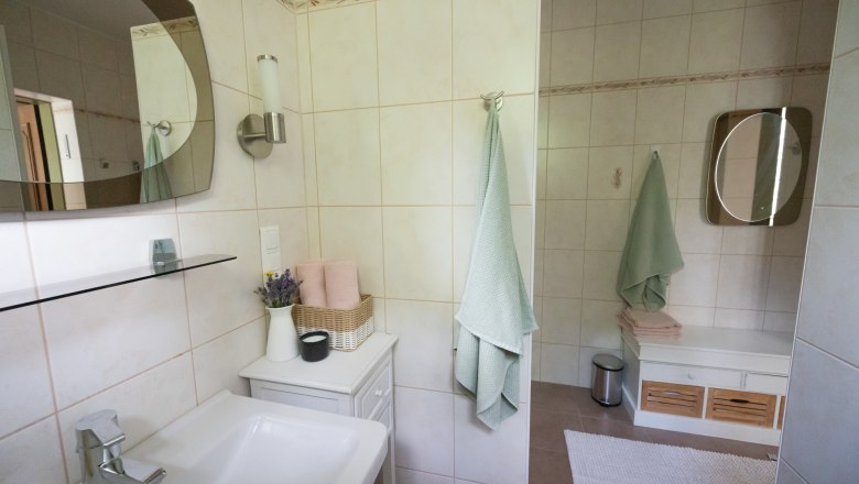 Modern bathroom with washbasin, mirror, towels and decoration.