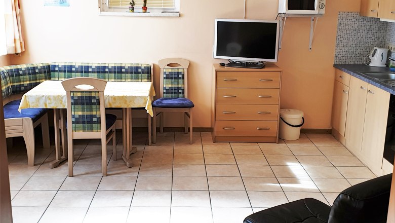 Kitchen, © Stern Kitchen with corner bench, table, chairs, TV, microwave and cupboards.