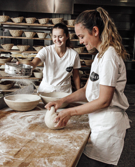Two women are baking in a bakery and kneading dough.