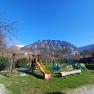 Children's playground with slide and swings against a mountain backdrop.