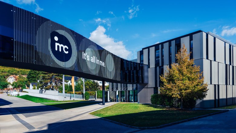 Modern IMC Krems building with glass bridge and 'It's all in me' lettering.