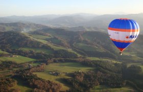 Hot air balloon over the green hilly landscape of the Traisental.