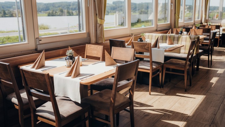Bright restaurant with wooden furniture and a view of the Danube.