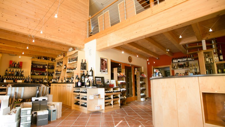 Interior view of a wine shop with wooden furnishings and wine bottles.