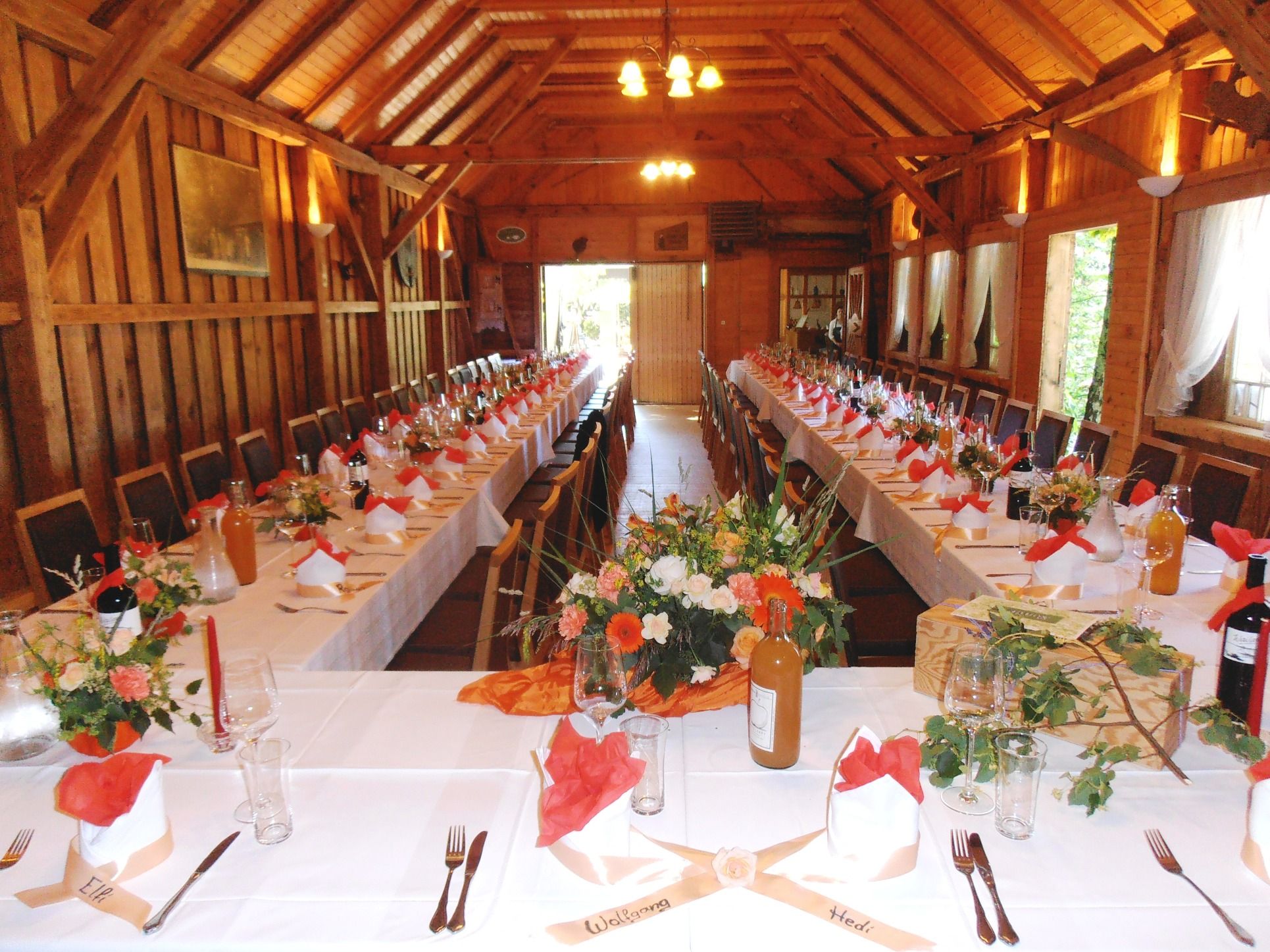 Interior view of a festively decorated hall with long tables and wooden ceiling.