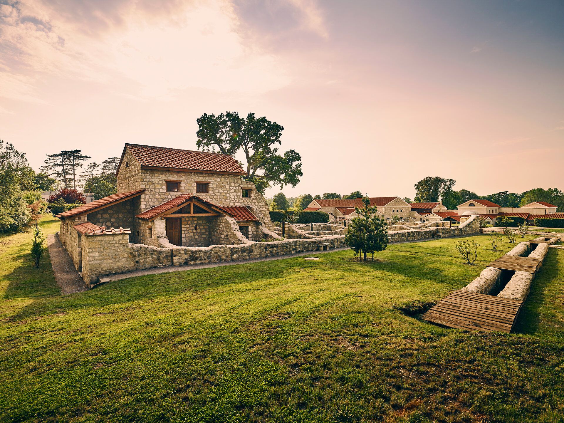 Roman town of Carnuntum with reconstructed buildings and red roofs, surrounded by green trees and lawns.