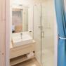 Modern bathroom with washbasin, mirror, shower and blue curtains.