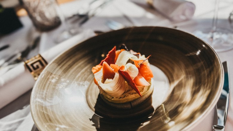 An artfully prepared dish on a brown plate in a restaurant.