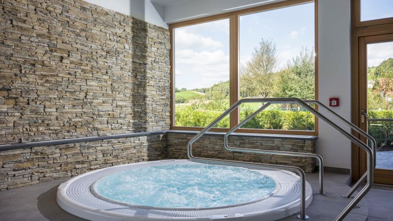Wellness room with whirlpool, stone walls and large window with a view of the countryside.