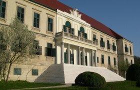 Loosdorf Castle with neoclassical façade and staircase, surrounded by a well-tended garden.
