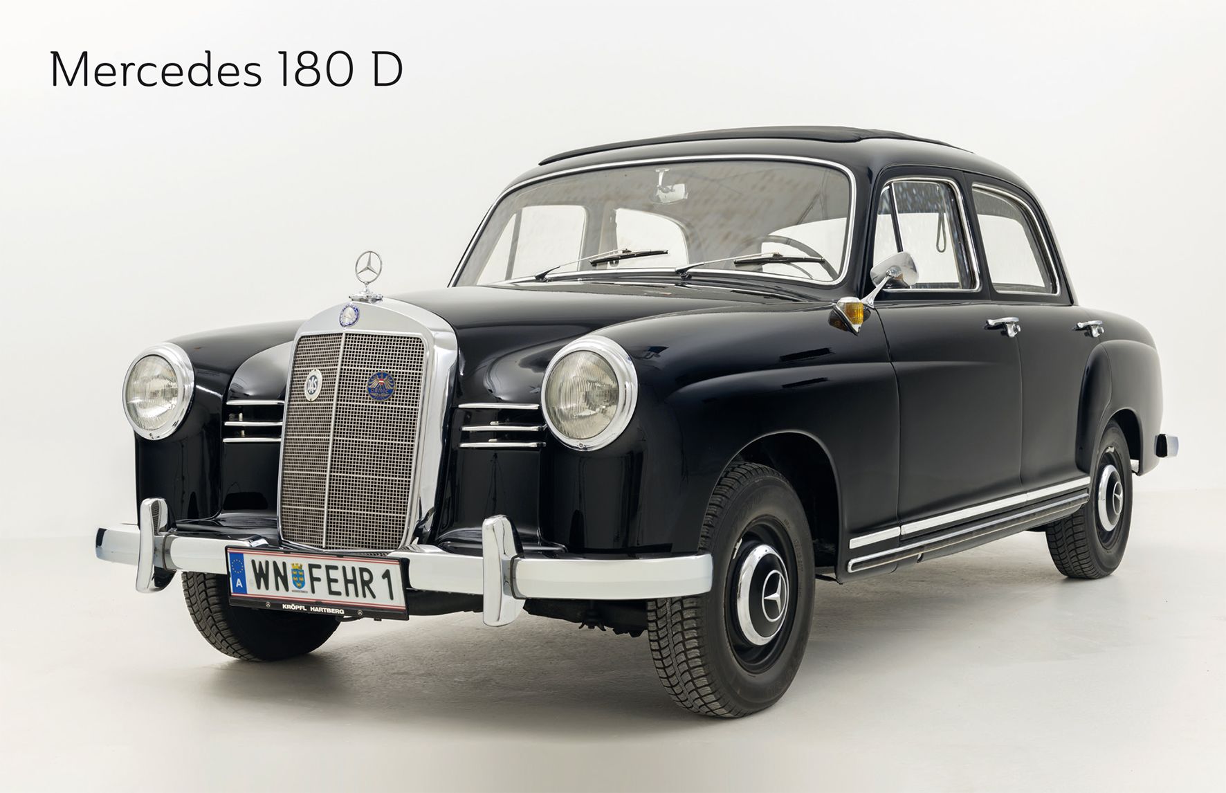 A black Mercedes 180 D vintage car in a studio with a white background.