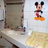 Child-friendly bathroom with Mickey Mouse decor and changing table.