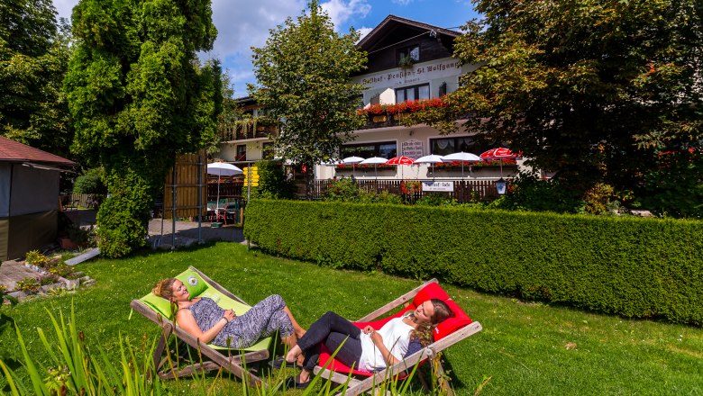 Two women relaxing in deckchairs in the garden of an inn.