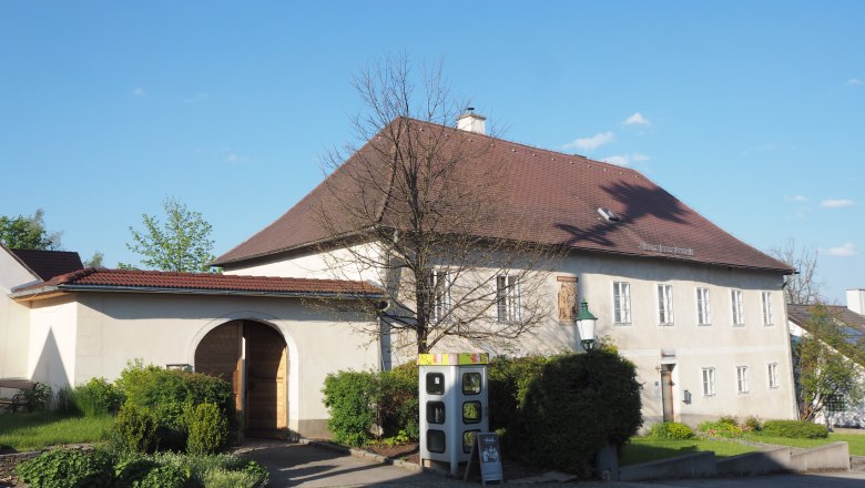 Historic building with archway and garden, blue sky.