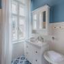 Bright bathroom with blue and white tiles, white washbasin and window with white curtains.