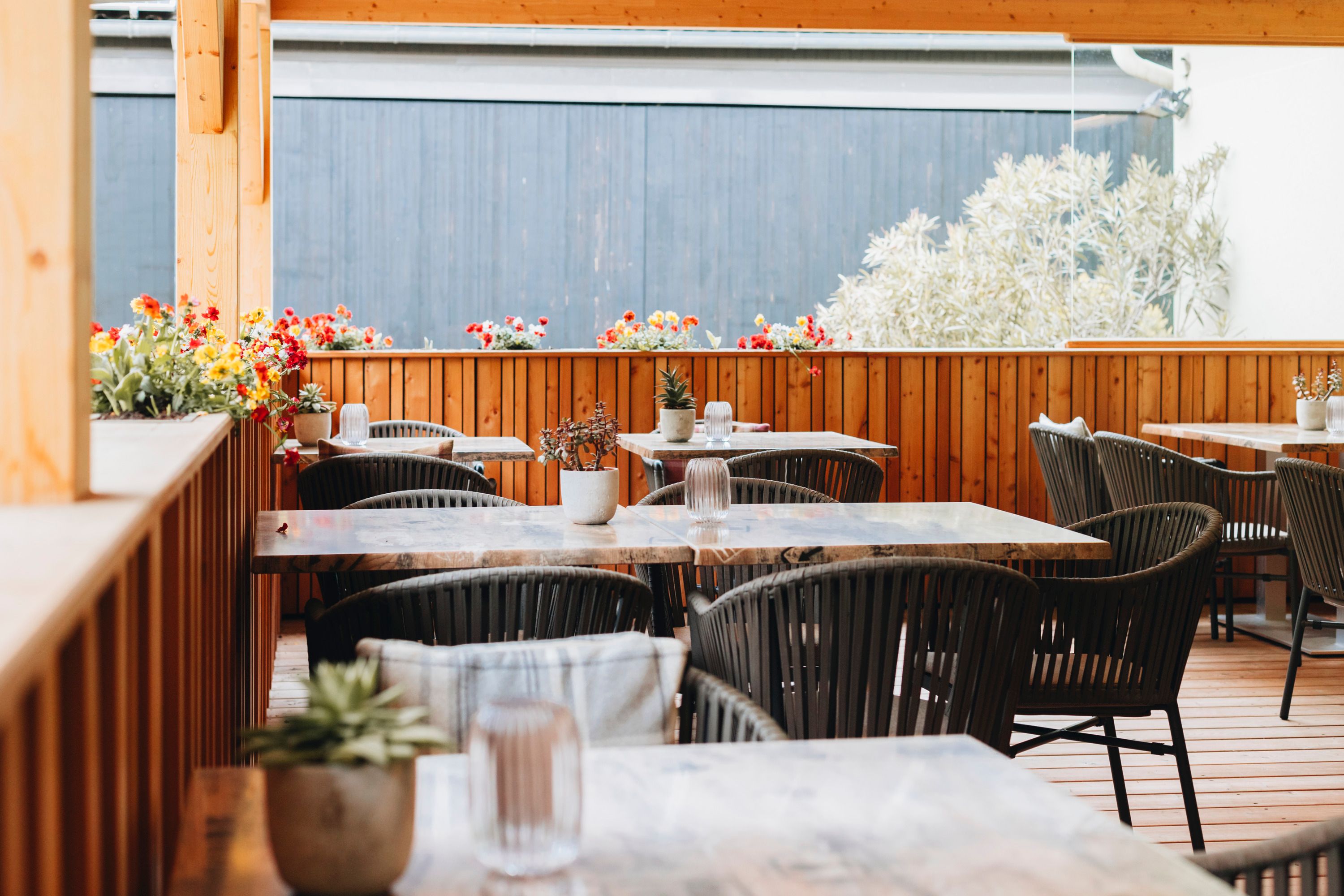 A cozy courtyard with wooden furniture and flower arrangements on the tables.
