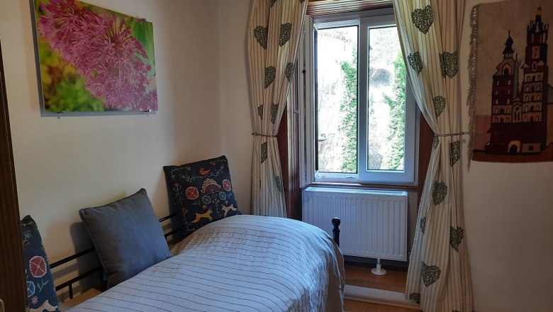 Single room with bed, window, curtains and wall decorations.