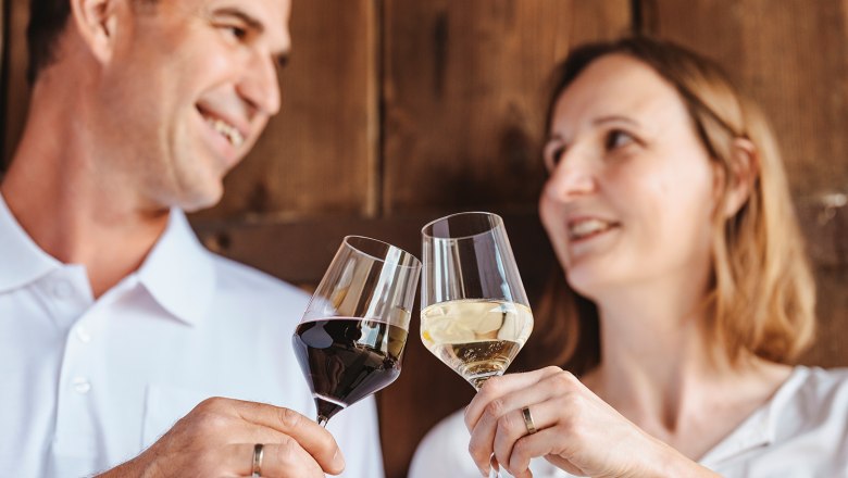 A man and a woman clink glasses of wine.