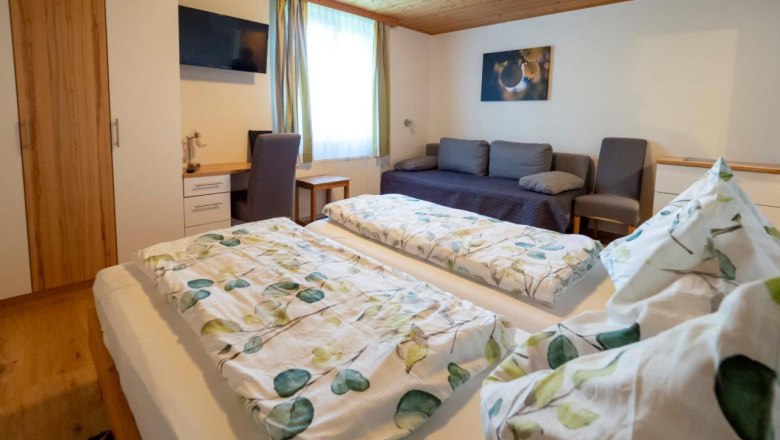 Comfortable guest room with double bed, sofa, desk and TV.