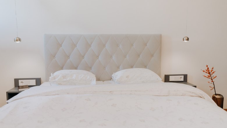 An elegant bedroom with a large bed, two bedside tables and a vase of red berries.