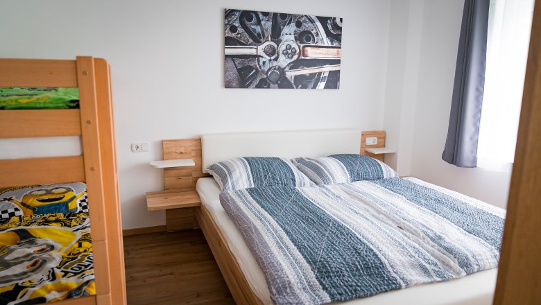 Bedroom with double bed, bunk bed and mural of a car part.