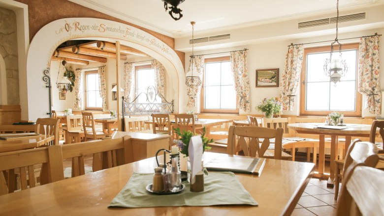 Interior view of a cozy restaurant with wooden furniture and floral curtains.