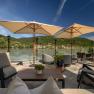 Terrace with a view of the Danube and surrounding hills, equipped with parasols and seating furniture.