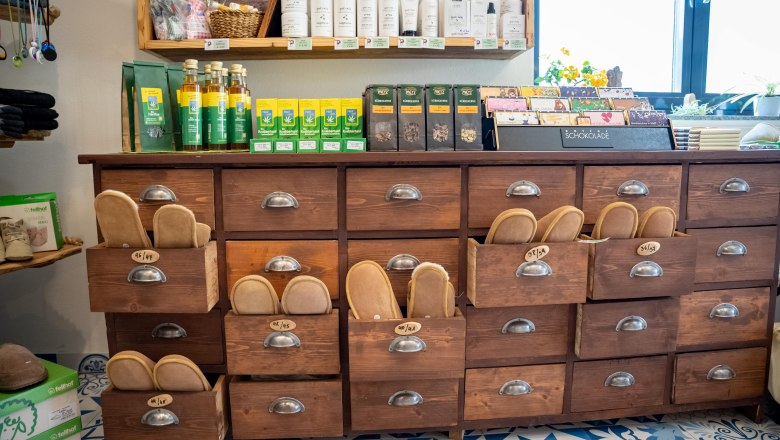 A shelf in a farm store with wooden drawers containing various products such as chocolate and care products.