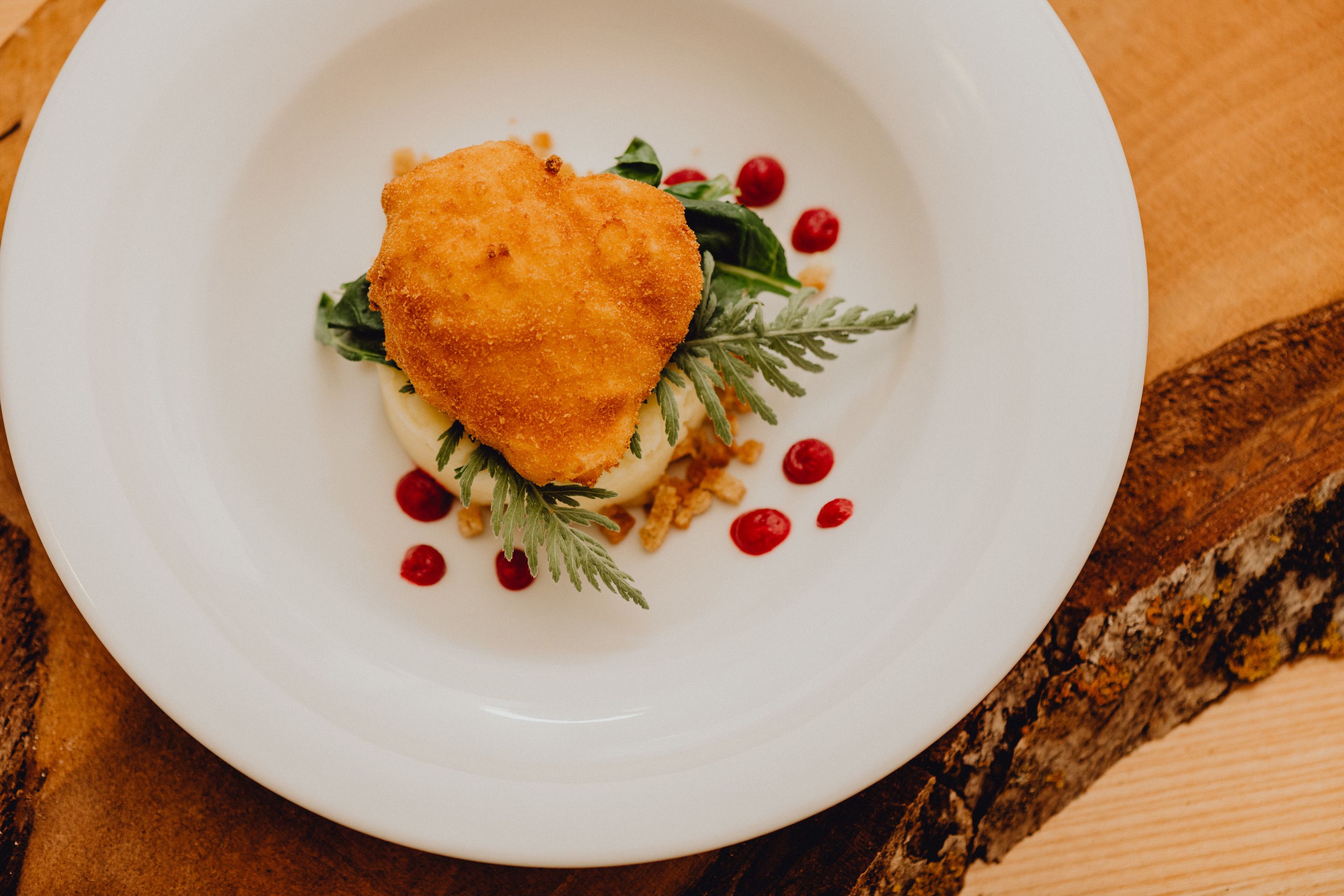 A baked egg on a plate with puree and red polka dots.
