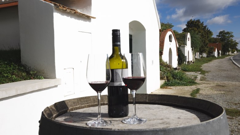 two wine glasses and a red wine bottle on a wine barrel, the wine cellar lane in the background
