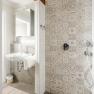 Modern bathroom with patterned tiles, washbasin and rain shower.