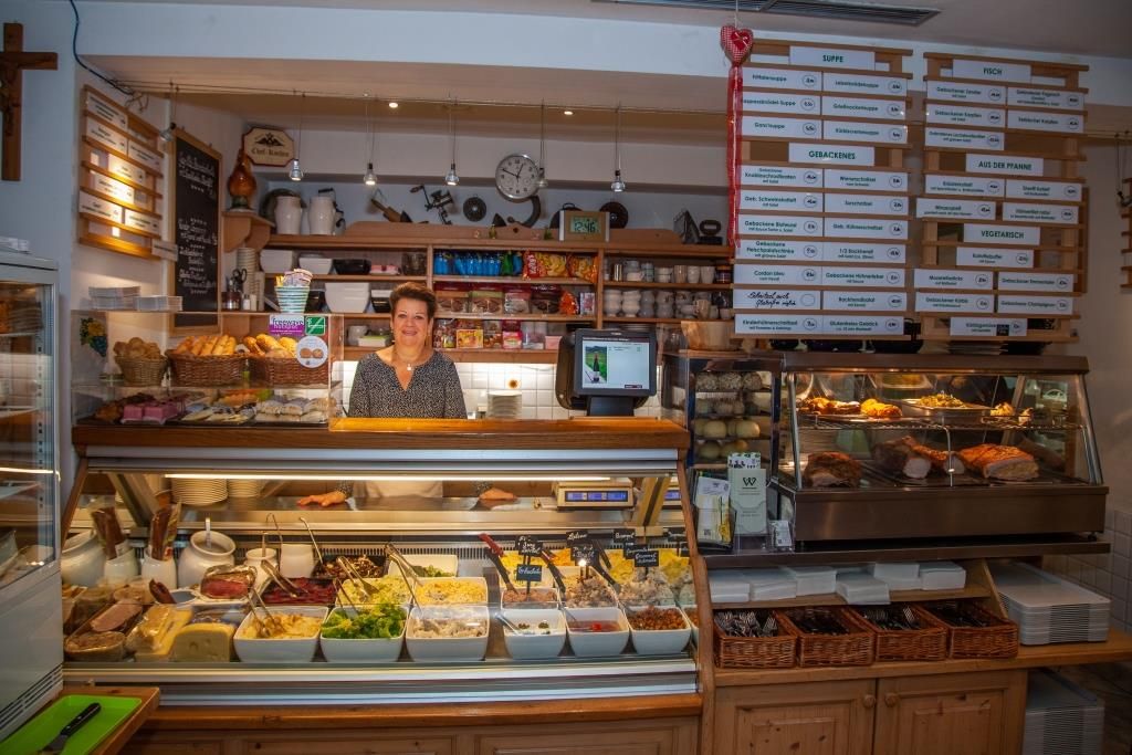 Woman behind a buffet with various dishes in a restaurant.