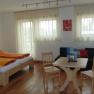 Bright room with double bed, table, chairs and sofa.