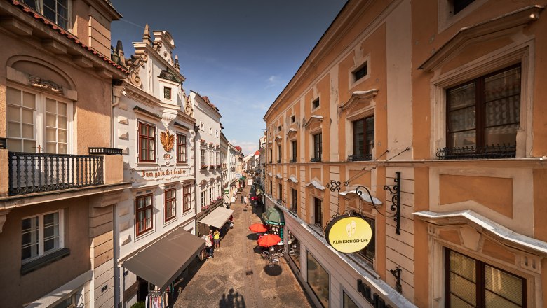 View of a historic street in the old town of Krems with old buildings and stores.