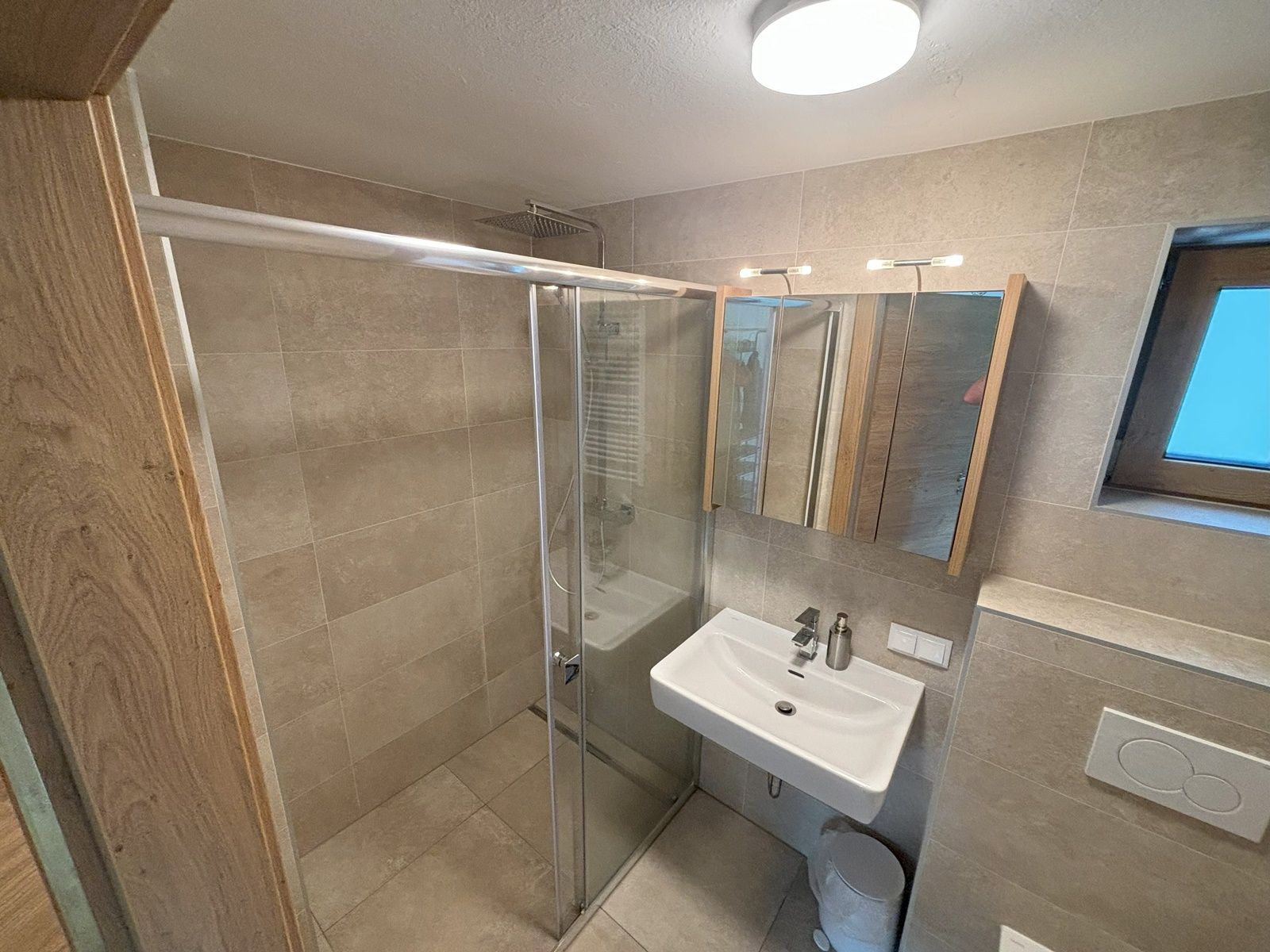 Modern bathroom with shower, washbasin and mirror.