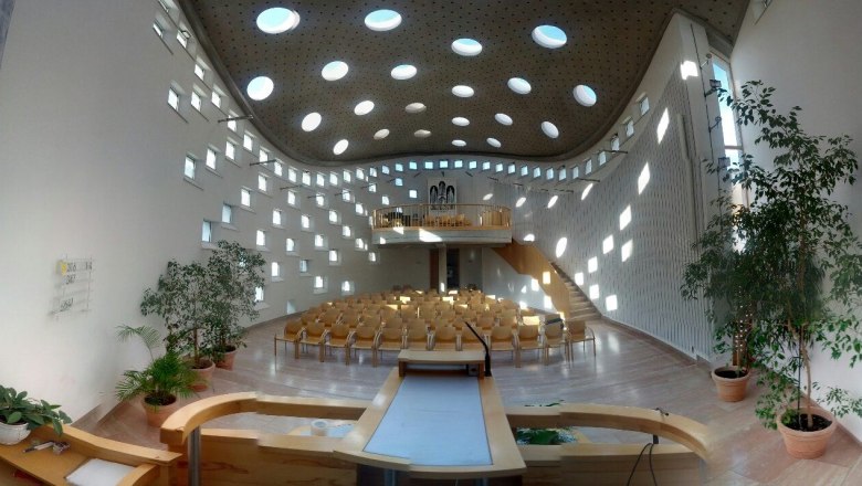 Modern church interior with round windows and wooden furniture.