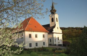 Church with vicarage in a rural setting, surrounded by trees and meadows.
