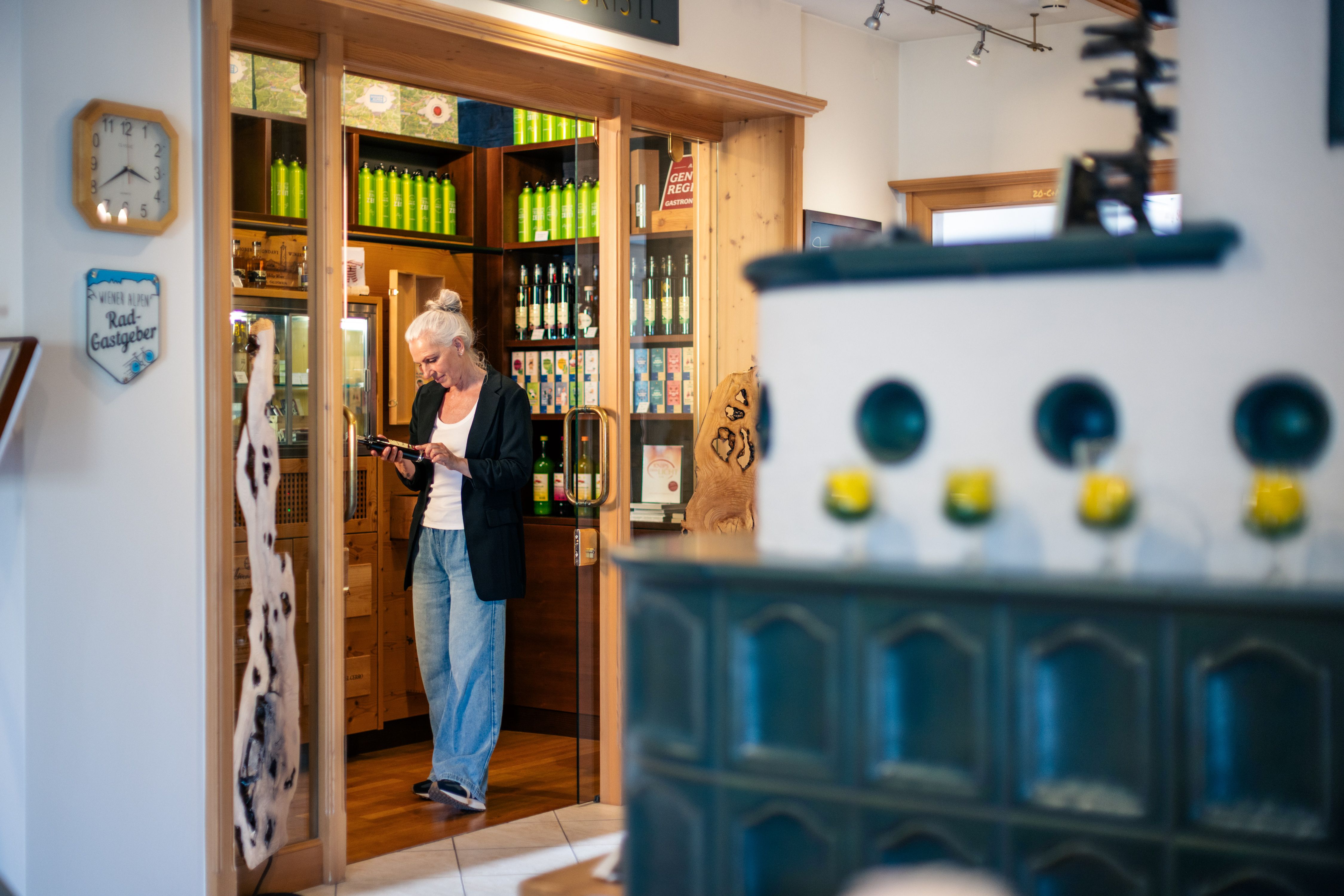 A woman is standing in a hotel shop, looking at a bottle on a shelf filled with drinks.