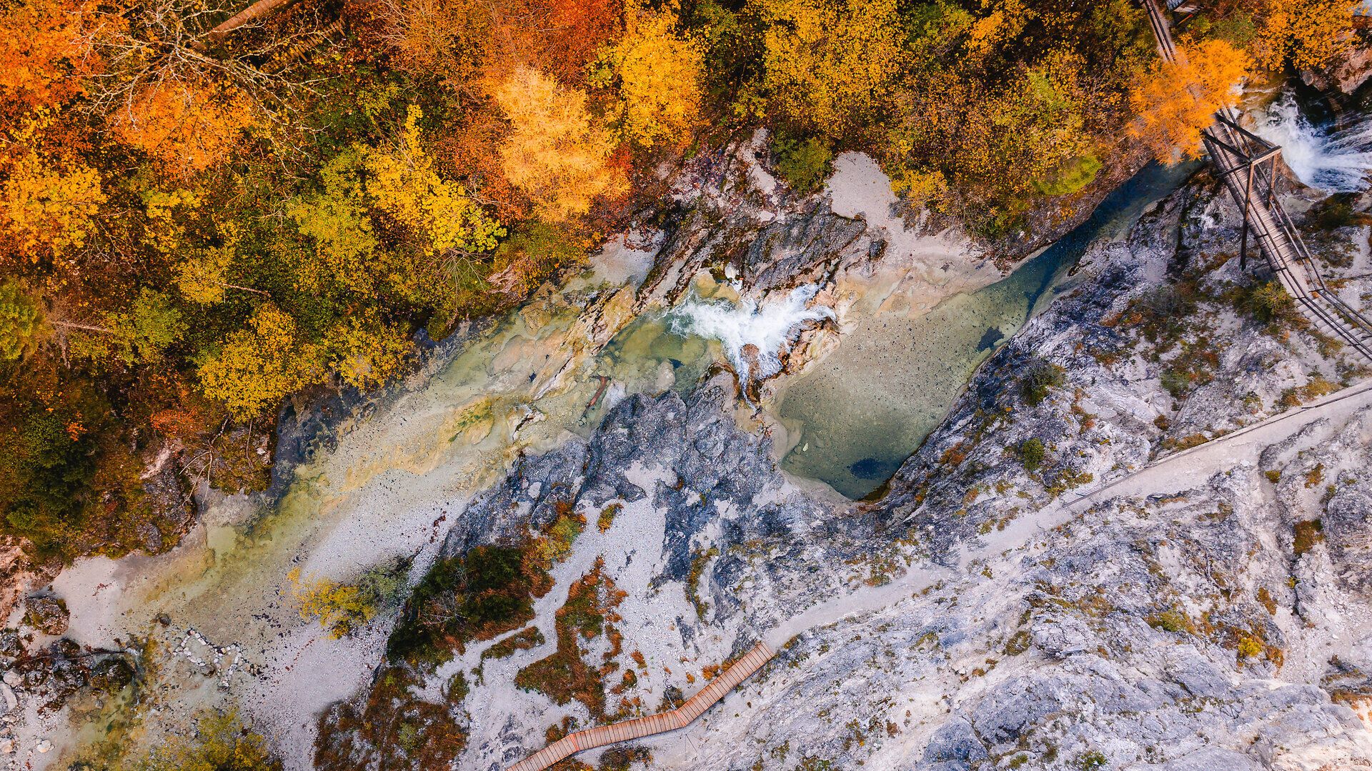 Die bunten Blätter der Bäume spiegeln die goldene Herbstsonne wider und schaffen eine malerische Kulisse für den klaren, plätschernden Bach, der durch die Schlucht fließt. Wanderer können die frische, klare Luft genießen und die beeindruckenden Felsformationen bewundern, die diesen Naturpark zu einem wahren Paradies der Blicke machen.