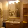 Bathroom with mirror, washbasin, tiles and shelf with towels.