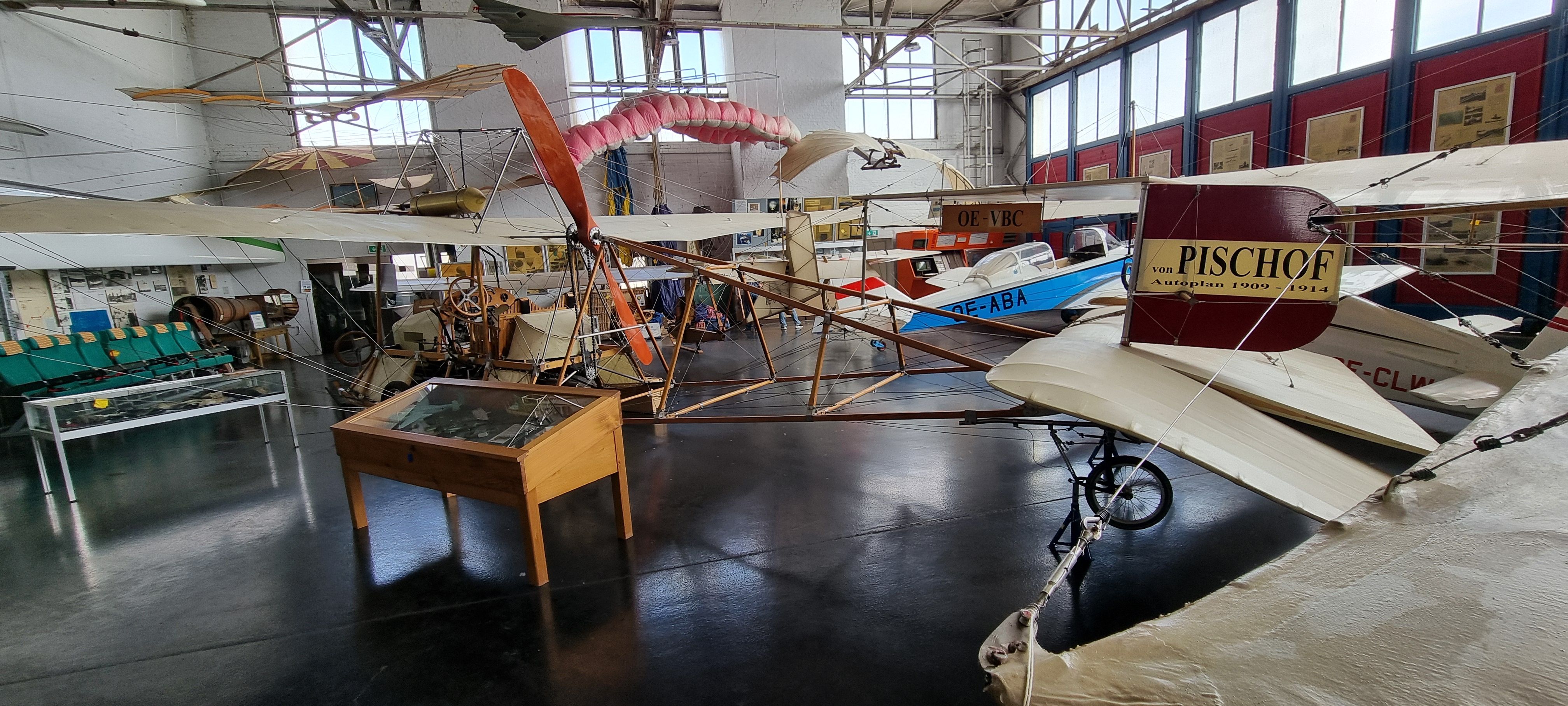 Large hangar with airplanes on the ground and hanging from the roof