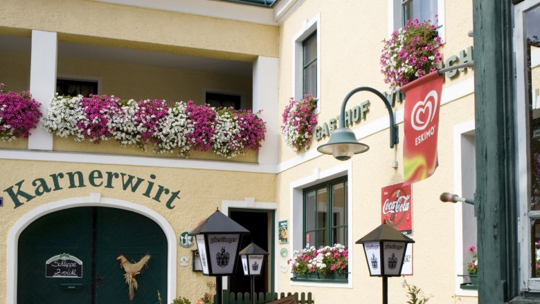 Entrance to an inn with flowers and advertising signs.