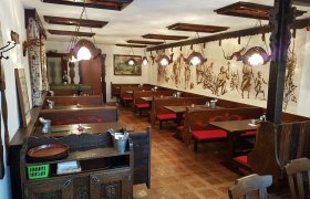Interior view of a traditional Buschenschank (typical tavern) with wooden furniture and wall paintings.