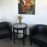 Two black armchairs and a round table with flowers in a room. An abstract painting with a fox motif hangs on the wall.