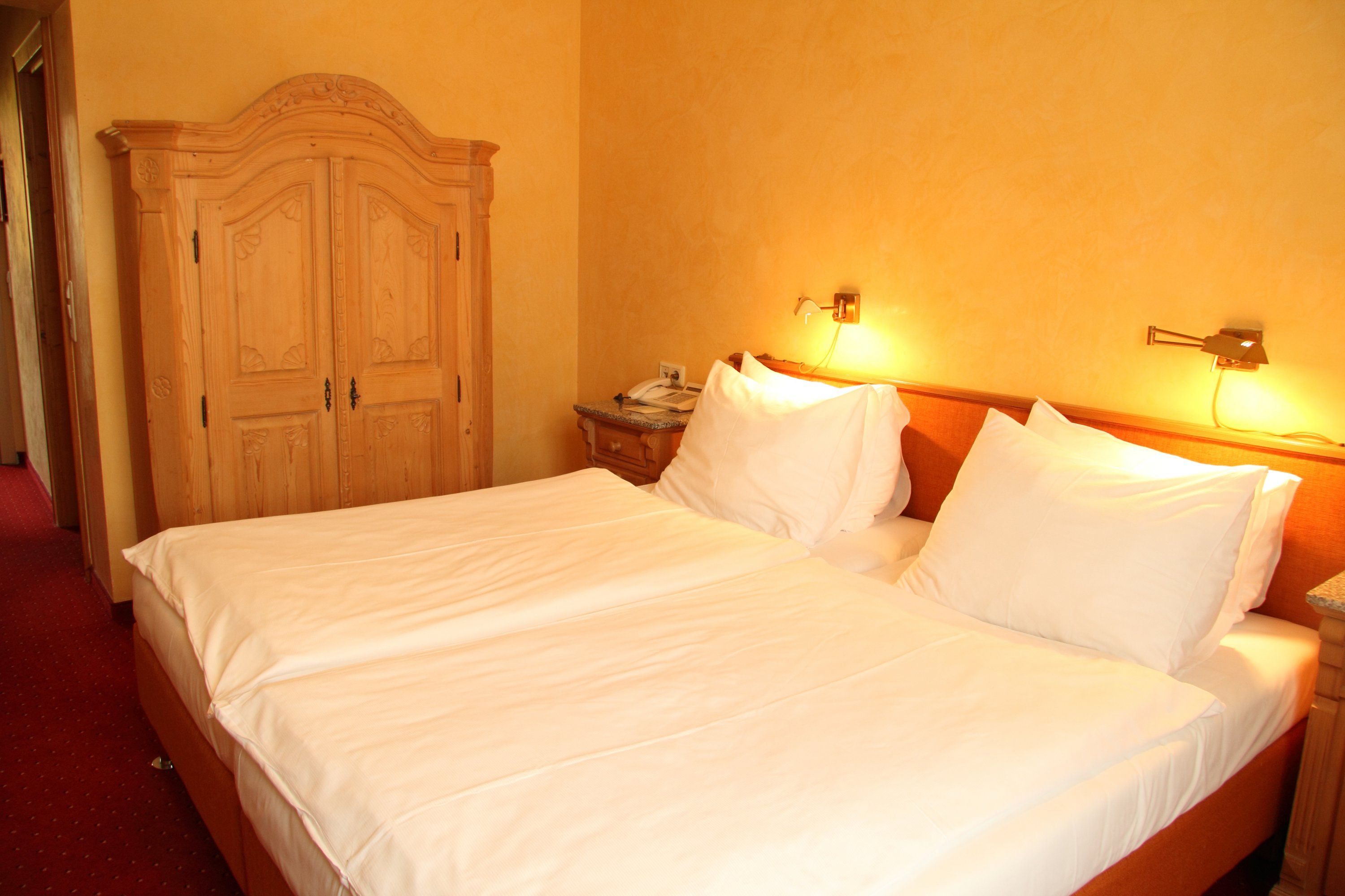 Hotel room with double bed, wooden furniture and warm light.